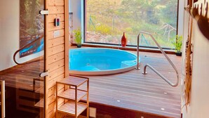 A wooden interior with a hot tub, wooden shelves, and a large window overlooking a natural landscape. - Auberge Alpina (Greolieres)