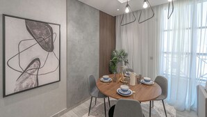 Un comedor moderno con una mesa redonda, sillas grises y un cuadro abstracto minimalista en la pared.