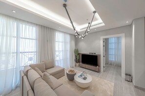 A modern living room with a sectional sofa, a flat-screen TV, a coffee table, and a chandelier. - Mabaat - Al Nuzhah - 561 (Riyadh)