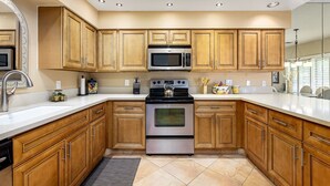 A modern kitchen with wooden cabinets, stainless steel appliances, and a white countertop.