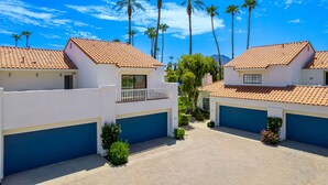 A residential area with two houses featuring red-tiled roofs, white walls, and blue garage doors.