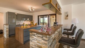 Een moderne keuken met een centraal eiland, inbouwapparatuur en een bar met krukken.