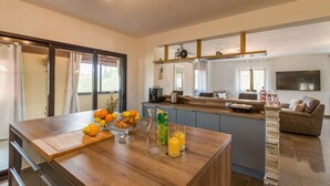 Een moderne keuken met een centraal eiland, een zithoek met een bank en een grote televisie aan de muur.