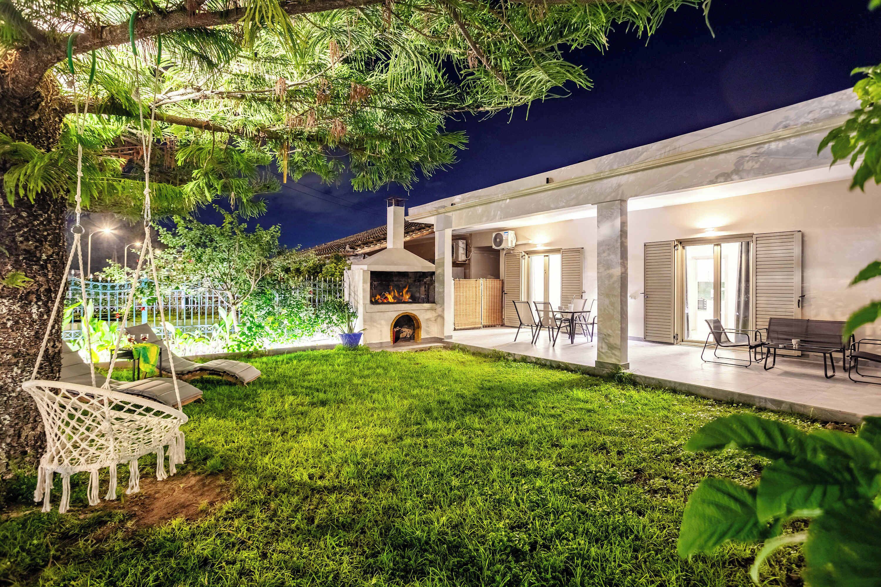A modern house with a well-maintained lawn, outdoor seating, and a fireplace.