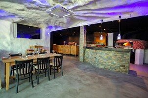 Un restaurante con un interior rústico, que presenta una mesa de comedor de madera, sillas y una pared de ladrillo.