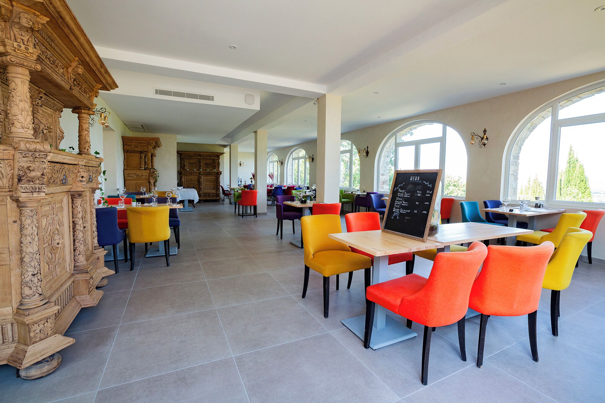 Une salle à manger spacieuse, dotée de hauts plafonds et de grandes fenêtres, et présentant un mélange de décorations modernes et traditionnelles.