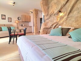 Un dormitorio con una cama grande, un comedor con mesa y sillas, un sofá y una cocina al fondo.