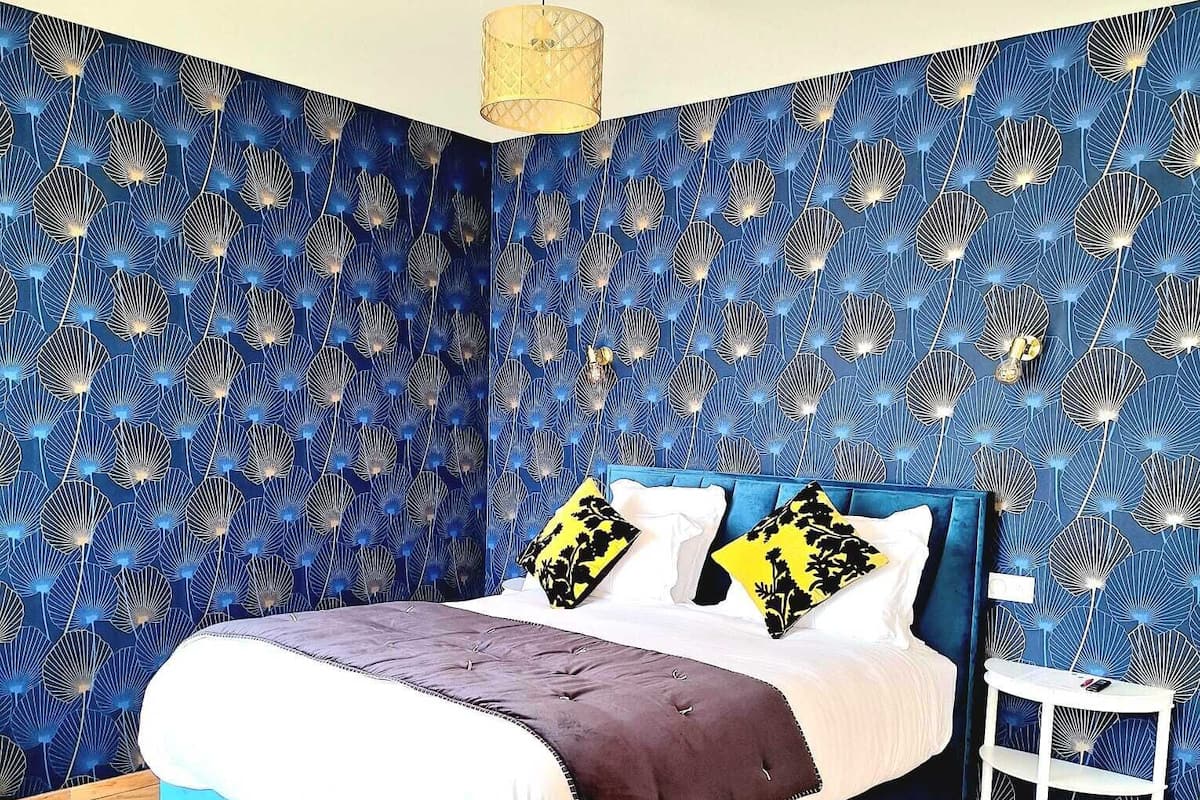 A bedroom with a bed, a nightstand, and a hanging light fixture.