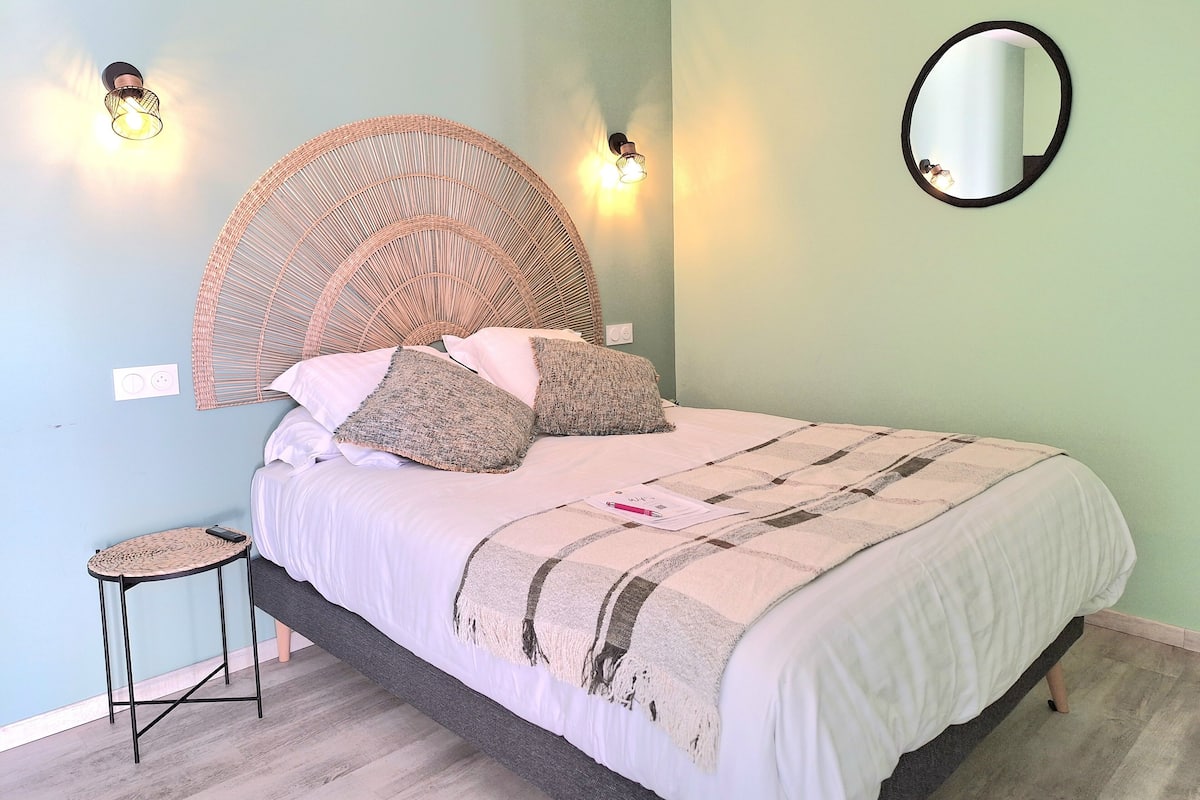 A bedroom with a bed, a round mirror, and two wall-mounted lights.