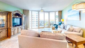 A spacious living room with a large flat-screen TV, comfortable seating, and a balcony with a view. - Caribe The Resort D401 2 Bedroom Condo (Orange Beach)