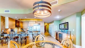 A spacious kitchen with modern appliances, a dining area with ornate chairs, and a bar area with a television.