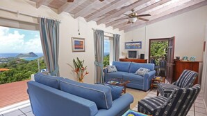 Una sala de estar con un sofá azul, sillones a rayas, una mesa de centro de madera y un televisor.