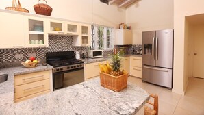 A kitchen with granite countertops, a stove, a microwave, a refrigerator, and wooden cabinets.