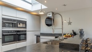 A modern kitchen with built-in appliances, a large island with a sink, and a skylight.