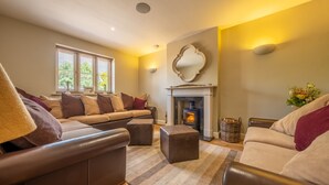 A cozy living room with a fireplace, leather sofas, and a striped rug.