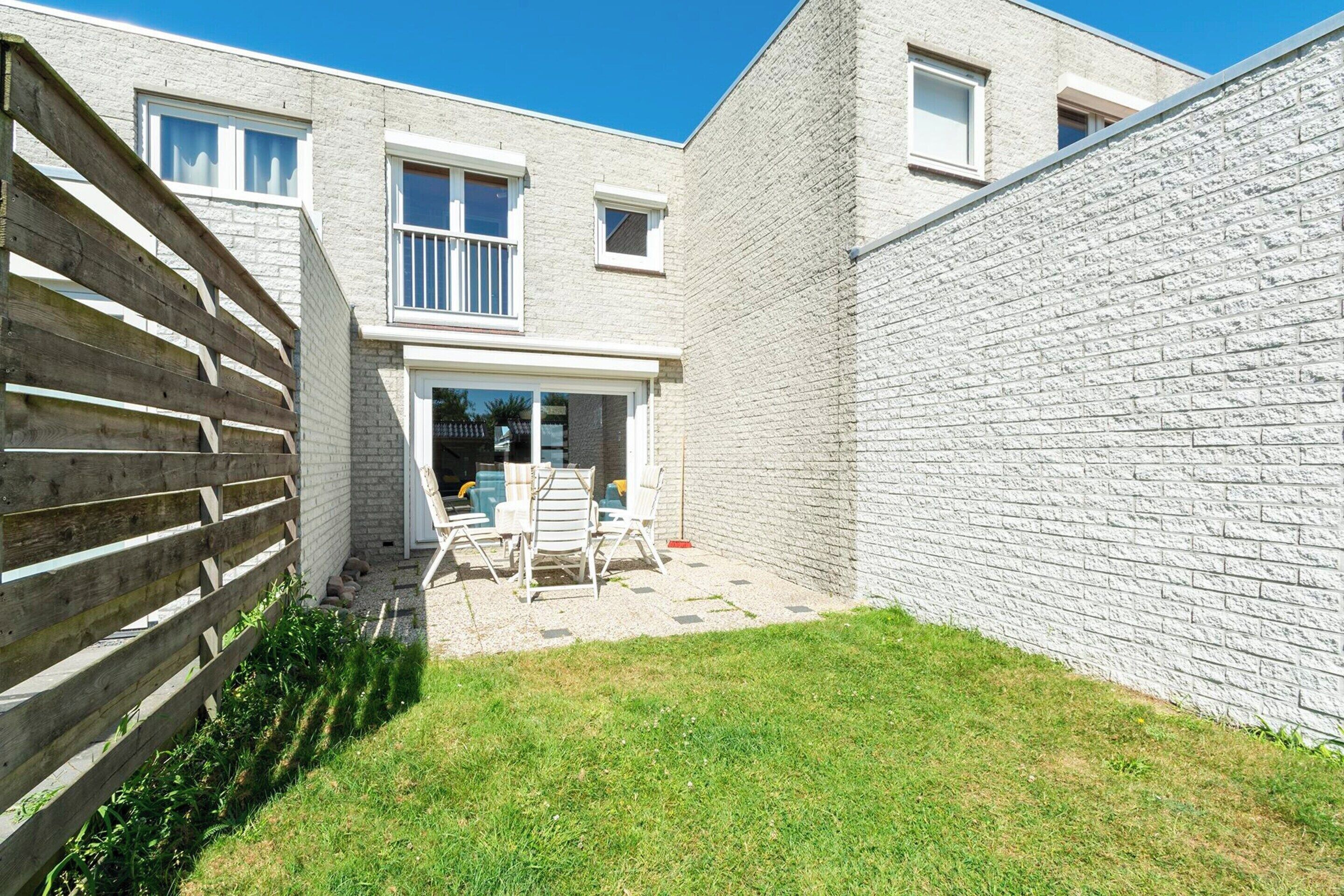 A modern house with a patio area featuring outdoor furniture.