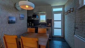 Una cocina compacta con comedor, que presenta una pared de piedra, una mesa de madera y un colgador de luz.
