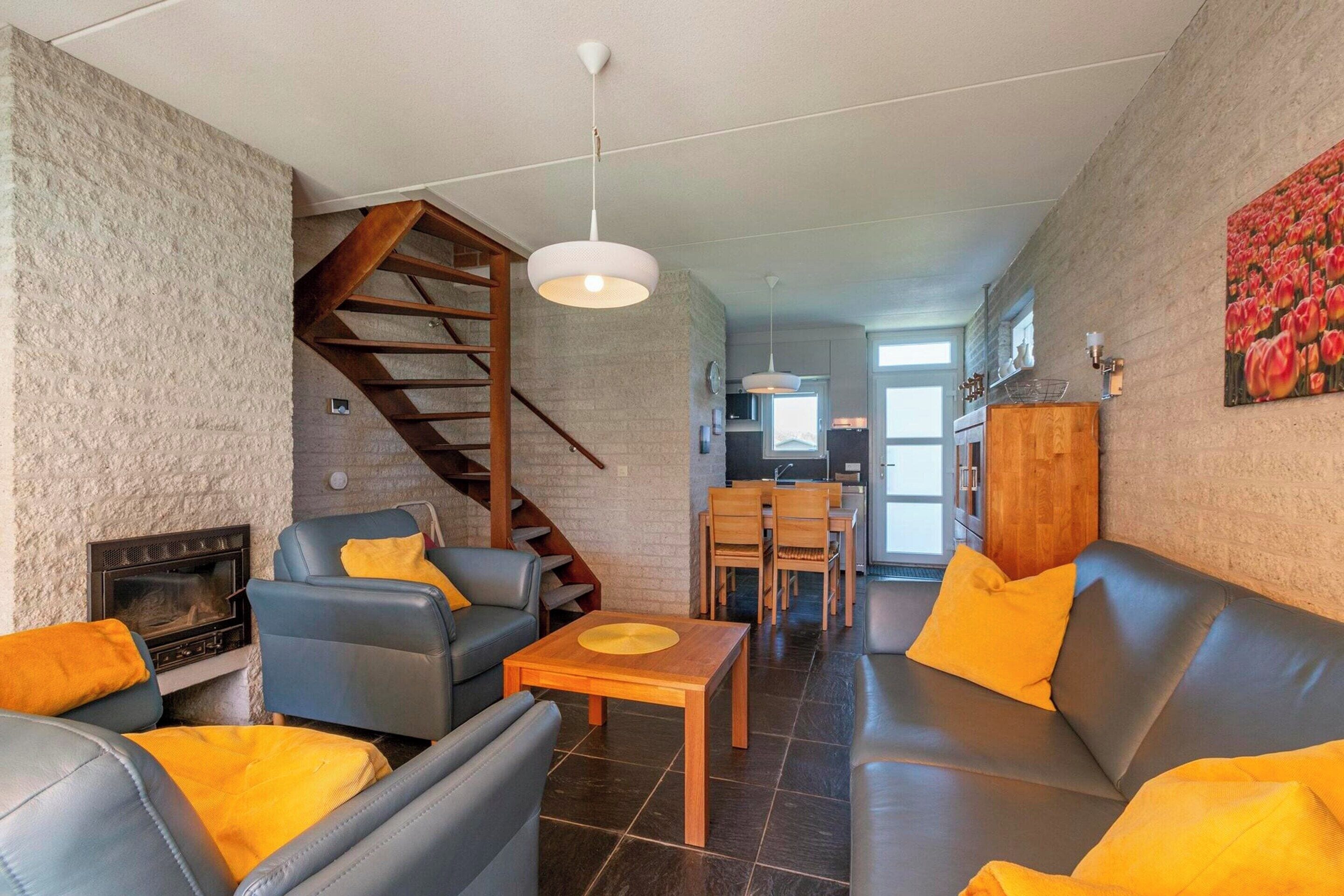 A modern living room with a fireplace, leather sofas, a wooden coffee table, and a staircase.