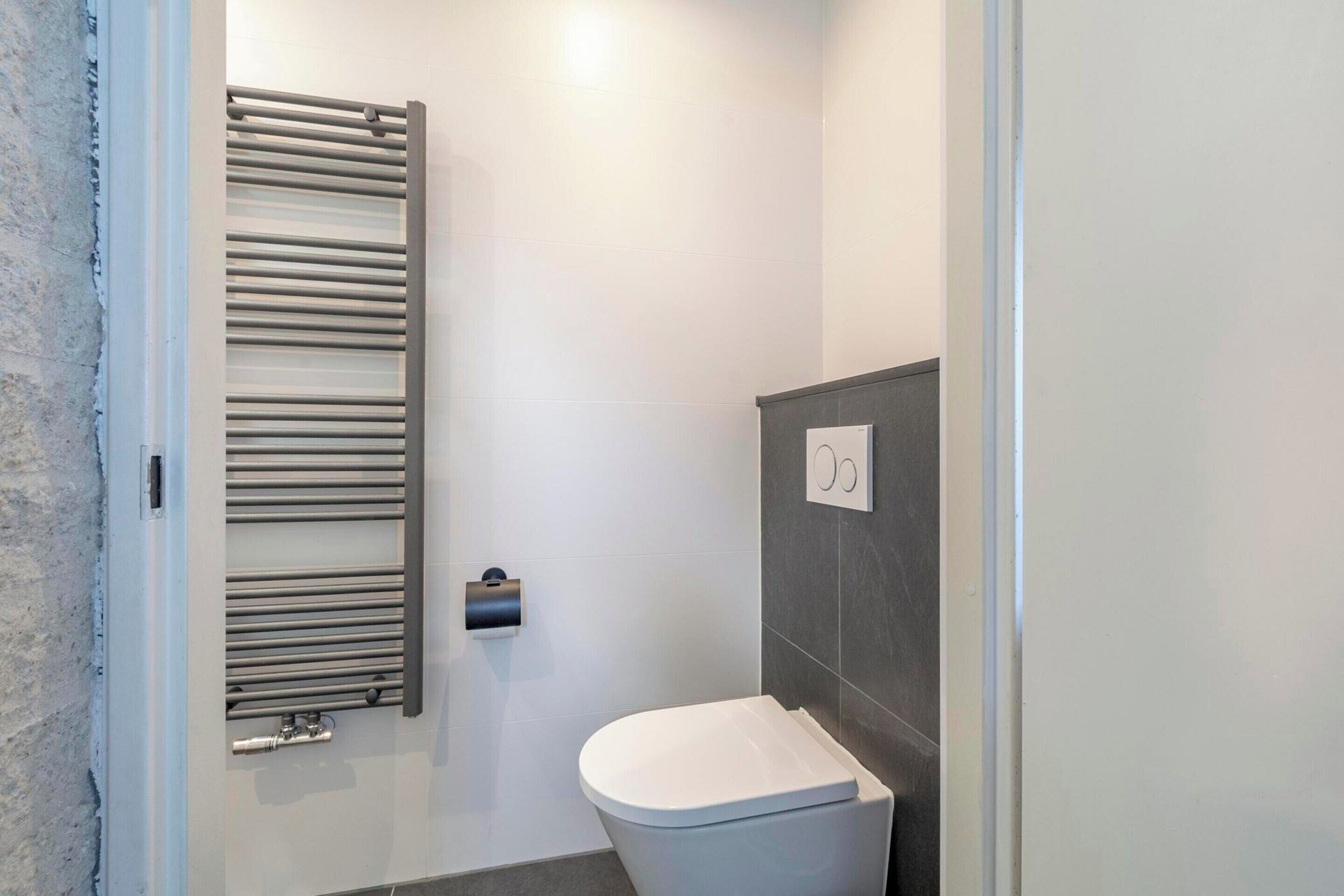 Un baño moderno con inodoro, toallero y panel de control en la pared.