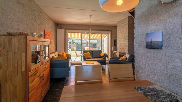 Una sala moderna con un aparador de madera, sofás azules, una mesa de centro de madera y una lámpara colgante grande.