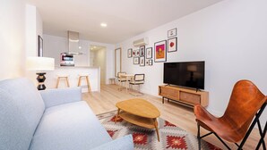 Een moderne woonkamer met een bank, salontafel, televisie en een eethoek met stoelen en een tafel.