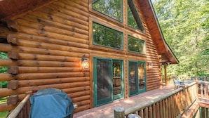 Eine Blockhütte mit einer Veranda, großen Fenstern und einer überdachten Terrasse.