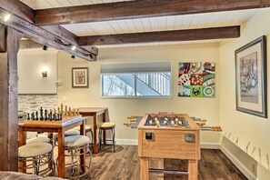 Relax in this inviting room with a foosball table, chessboard, and bar area, surrounded by artwork and natural light.