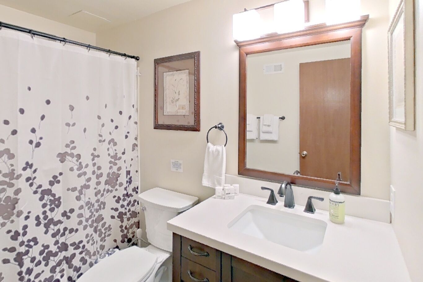 Une salle de bain équipée d’un rideau de douche, de toilettes, d’un lavabo et d’un miroir.