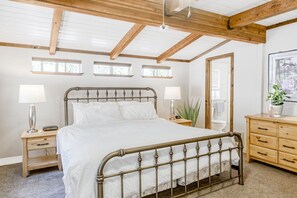 Relax in this serene bedroom with a large bed, two bedside tables, and a dresser.