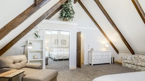 Una camera da letto con soffitto a vista, un divano, un letto, una cassettiera e uno specchio.