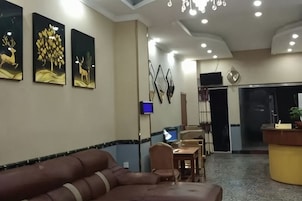 Un vestíbulo de hotel con mostrador de recepción, zona de estar y obras de arte en las paredes.