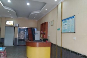 Zona de recepción con mostrador, un panel informativo en la pared y una puerta que da a un ascensor.