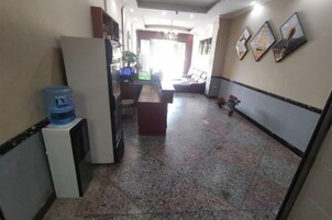 Un pasillo con dispensador de agua, mostrador de recepción y cuadros en la pared.