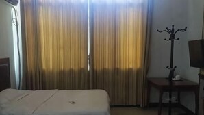 Ένα δωμάτιο ξενοδοχείου με δύο κρεβάτια, μια κρεμάστρα για παλτό, ένα μικρό τραπέζι και μια τηλεόραση.