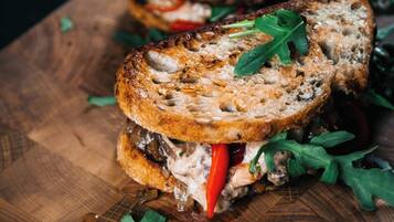 Ein Sandwich auf einer Holzplatte mit Rucola-Blättern.