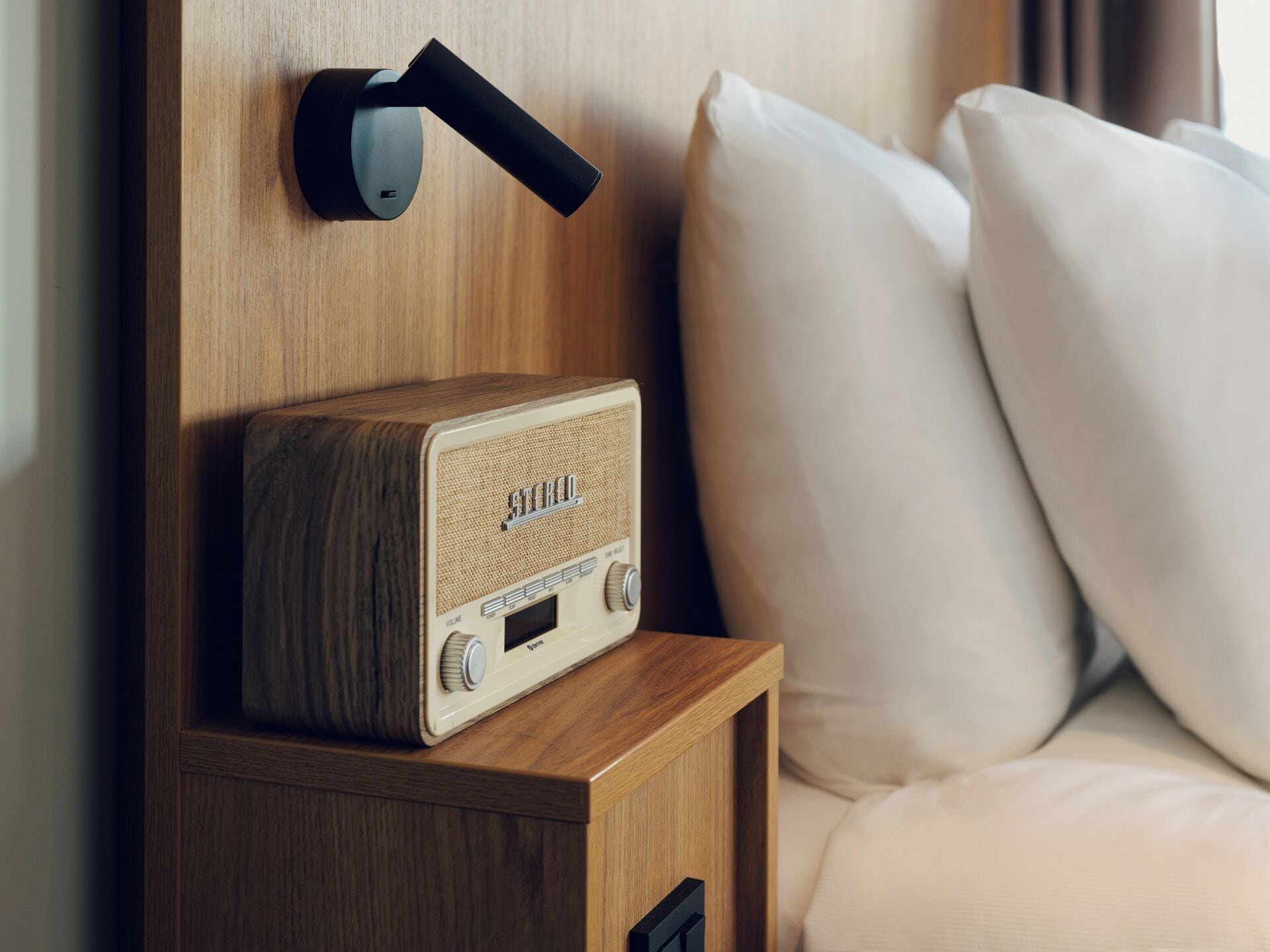 Ein Nachttisch aus Holz mit einem Vintage-Radio und einem modernen Türgriff.