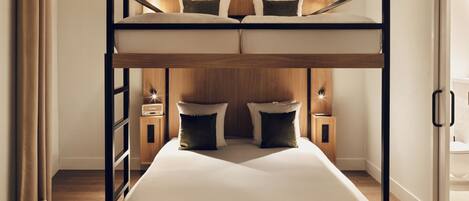 A bunk bed with a wooden headboard, two bedside tables with lamps, and a potted plant.