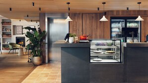 Egy modern konyha központi szigettel, függesztett lámpákkal és egy vitrinnel, amelyben sütemények vannak kiállítva.