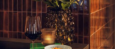 A table with a floral arrangement, a wine glass, a candle, and a bowl of food.