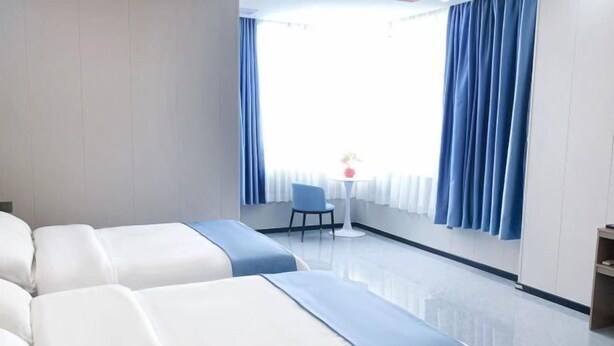A hotel room with two beds, a small table with a chair, and a window with curtains. - Xinduhui Hotel Shenzhen Dafen Metro Station (Shenzhen)