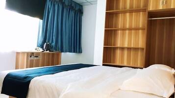 Quarto de hotel com uma cama, uma escrivaninha e um guarda-roupa.