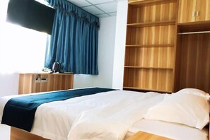 Una habitación de hotel con una cama, un escritorio y un armario.