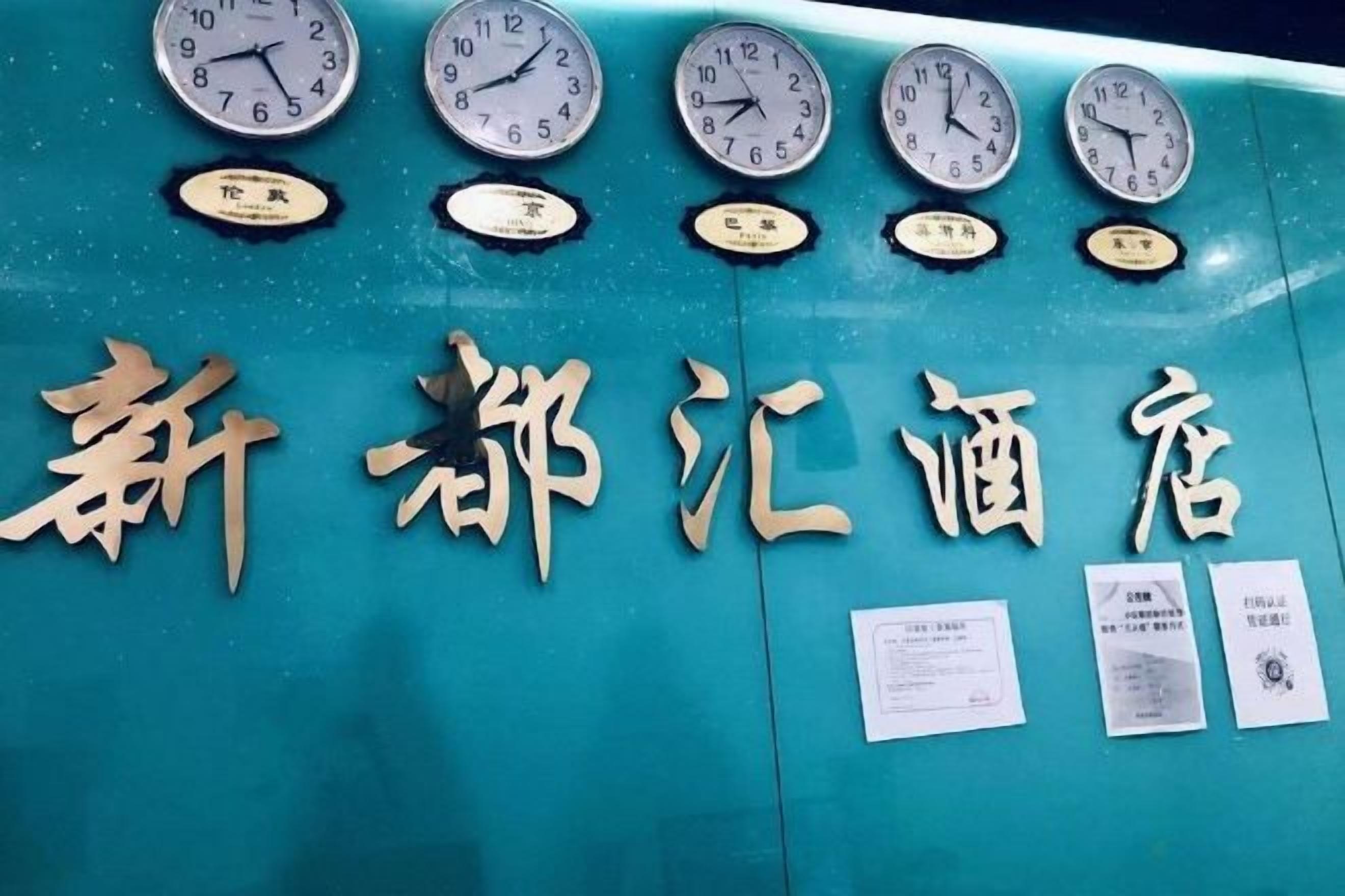 A wall with multiple clocks and Chinese characters, indicating a hotel setting.