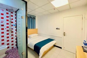 Una habitación de hotel con una cama, zona de ducha y una puerta.