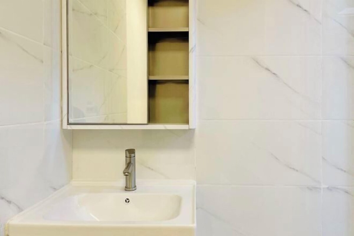 Un baño con un lavamanos blanco, un espejo encima y un estante con cajas de almacenamiento.