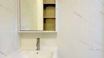 Un baño con un lavamanos blanco, un espejo encima y un estante con cajas de almacenamiento.