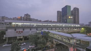 A modern train station with a covered pedestrian bridge and a high-rise building in the background.