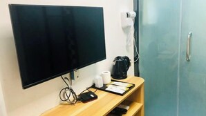 A room with a flat-screen TV, a coffee maker, a phone, and a cabinet. - Xinduhui Hotel Shenzhen Dafen Metro Station (Shenzhen)