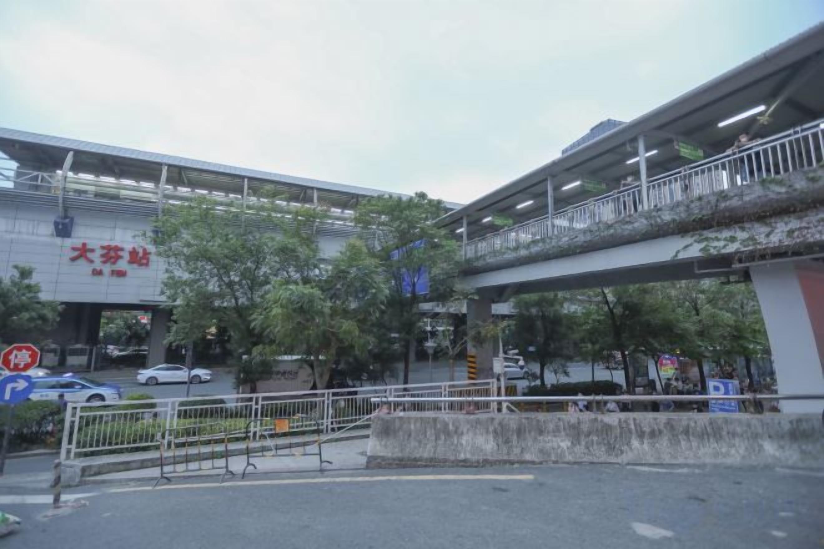 A multi-level pedestrian bridge with railings, a road below, and a building with signage.