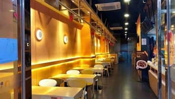 A restaurant interior with tables and chairs, a counter, and a staircase leading to an upper level.